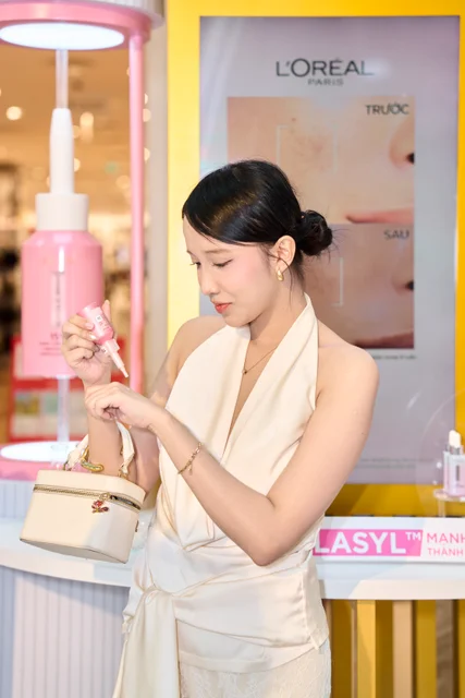 A guest exploring a pink L’Oréal Paris serum beside the gold product display